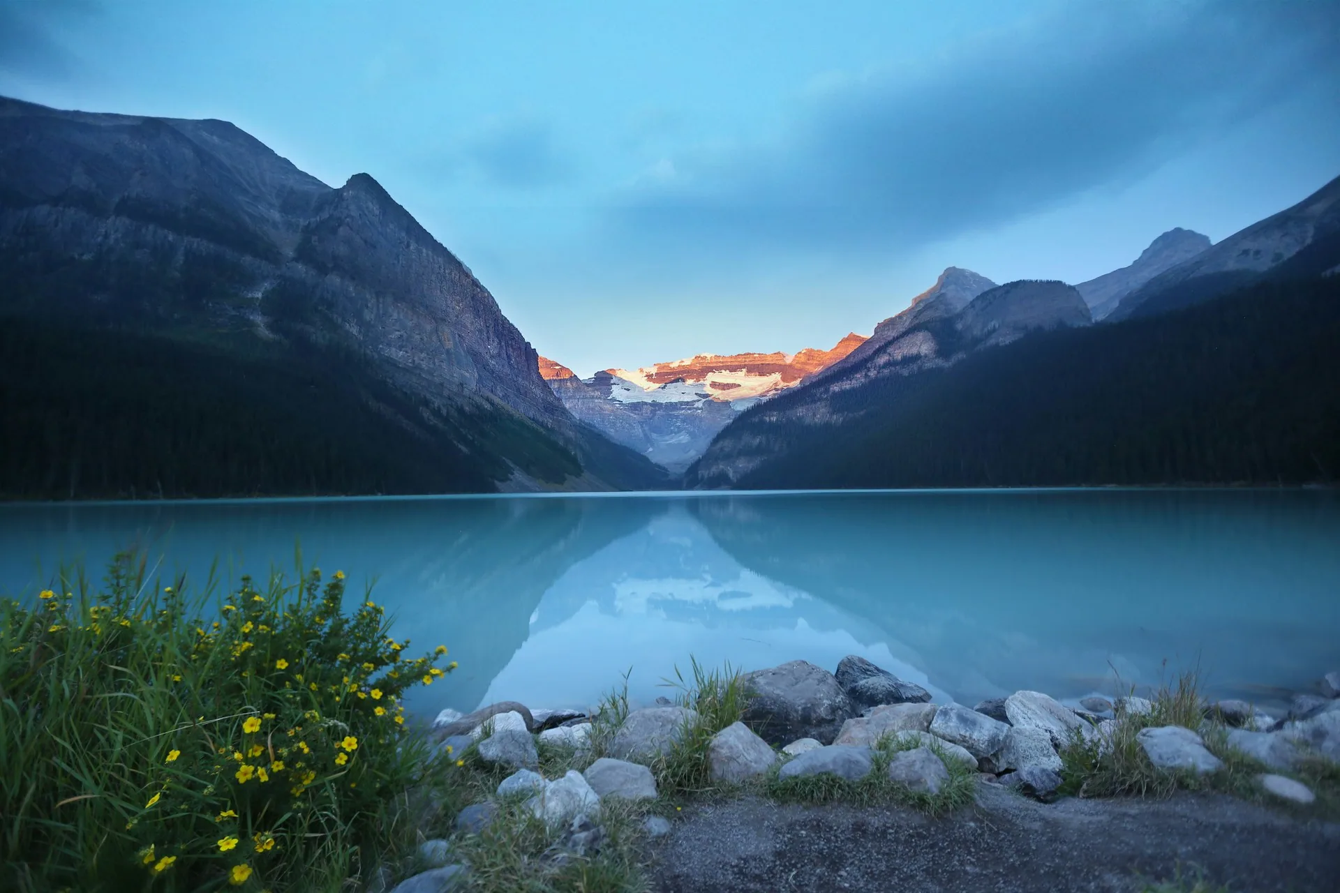Snow-dusted mountains reflected in a still lake at dusk