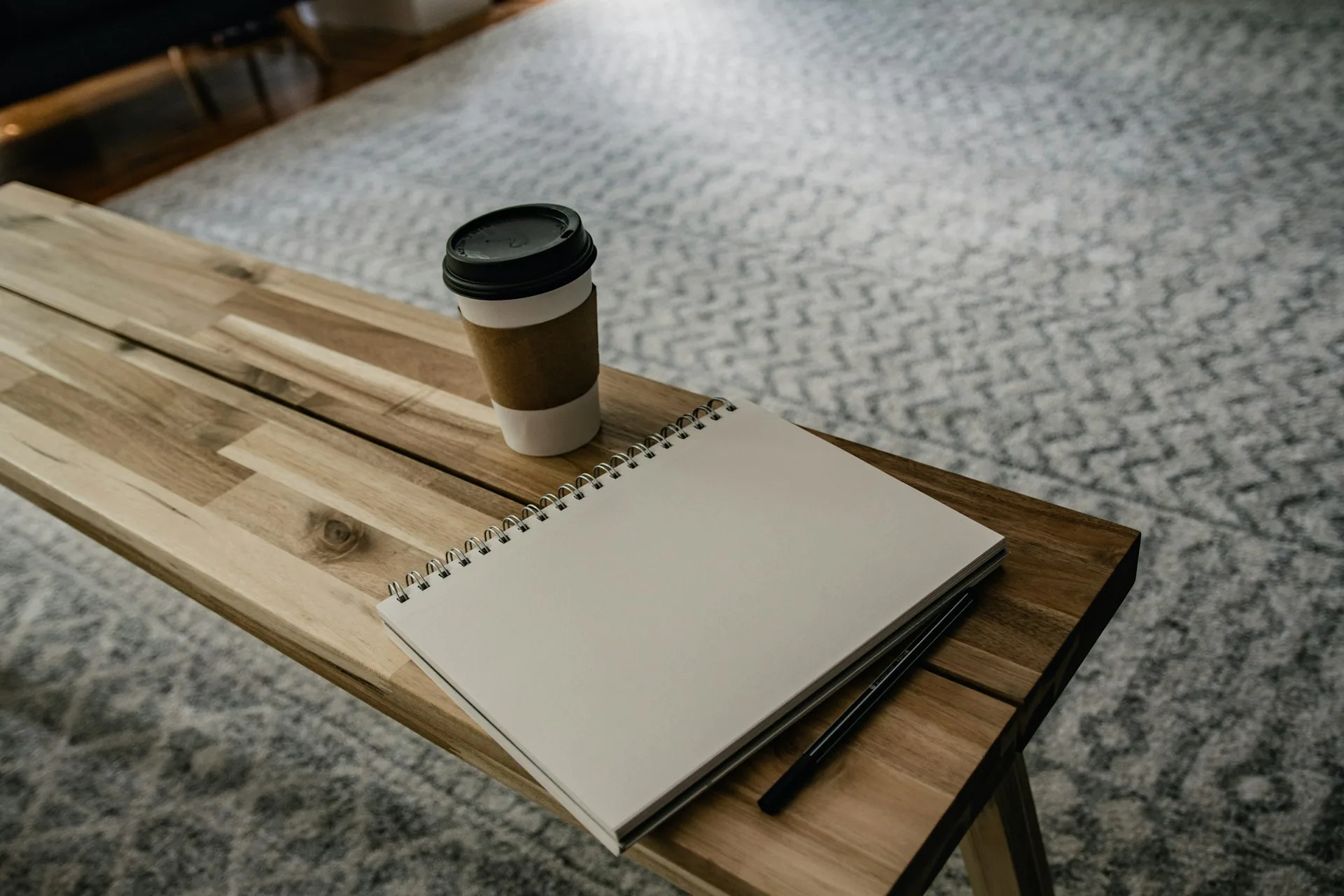 Notebook and takeaway coffee on a wooden desk